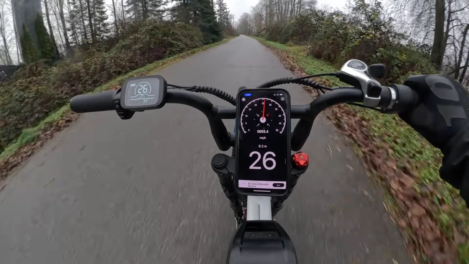 Handlebar view with a phone speedometer showing 26 mph