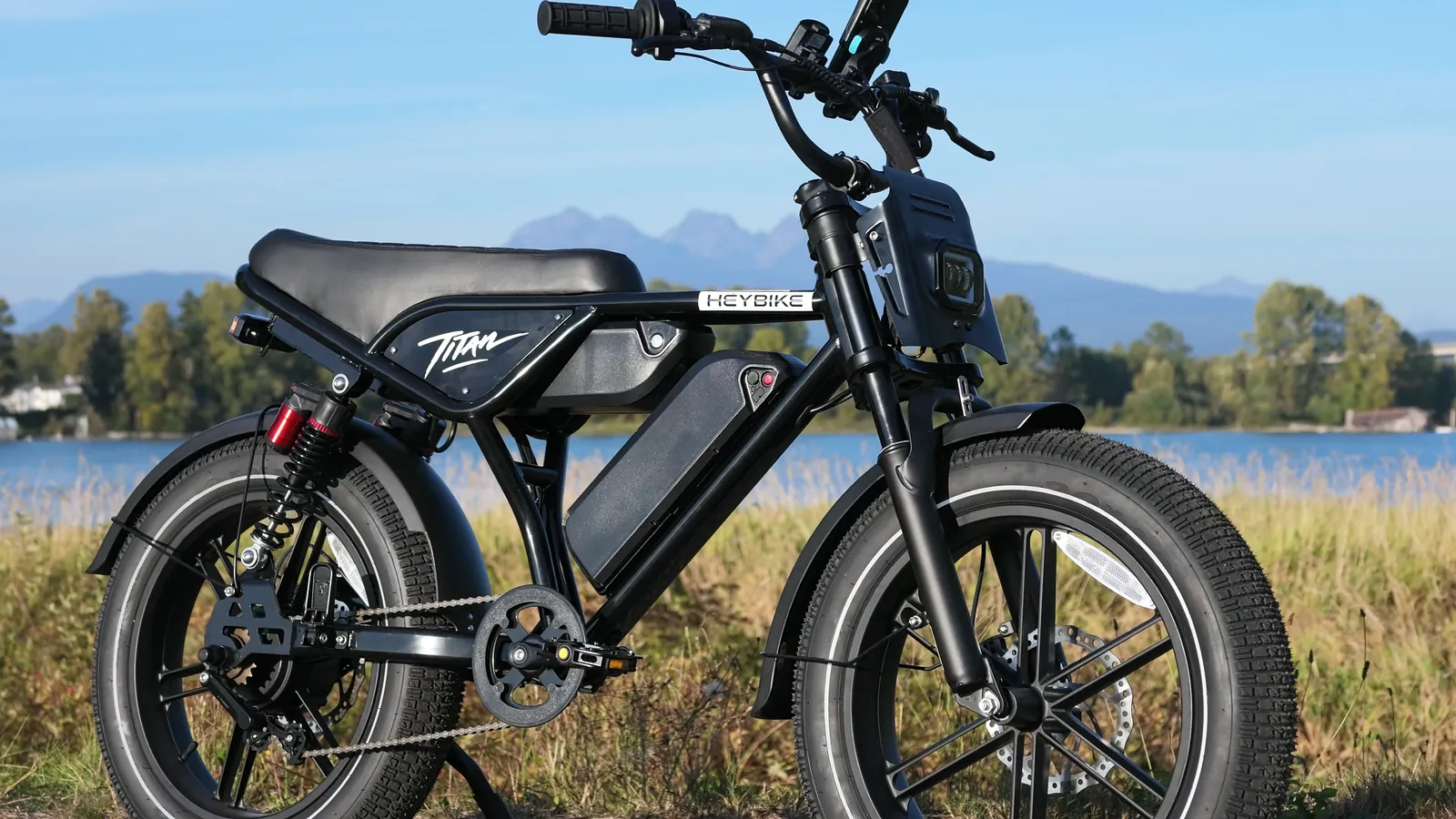 Heybike Titan parked by the river with mountains behind, front three-quarter view
