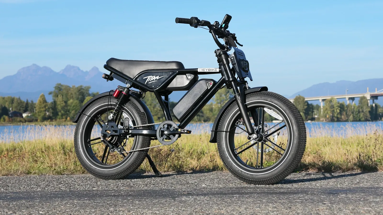 Heybike Titan side profile on a gravel path with mountains and a bridge behind